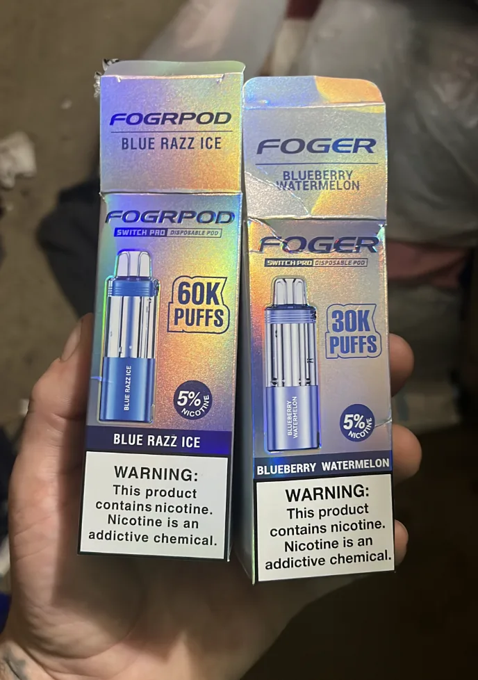 Customer photo comparing a counterfeit FOGRPOD Blue Razz Ice 60K puffs Switch Pro pod box with a genuine FOGER Blueberry Watermelon 30K puffs Switch Pro pod box